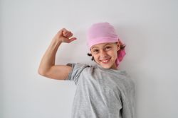 Joyful little boy smiling brightly and showing bicep