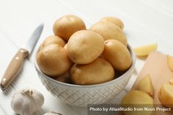 Bowl full of potatoes on kitchen counter with garlic and knife 5pwLg0