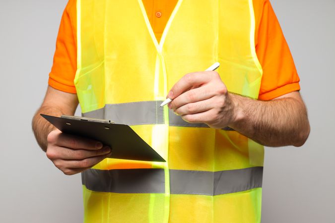 Civil engineer with clipboard on gray background