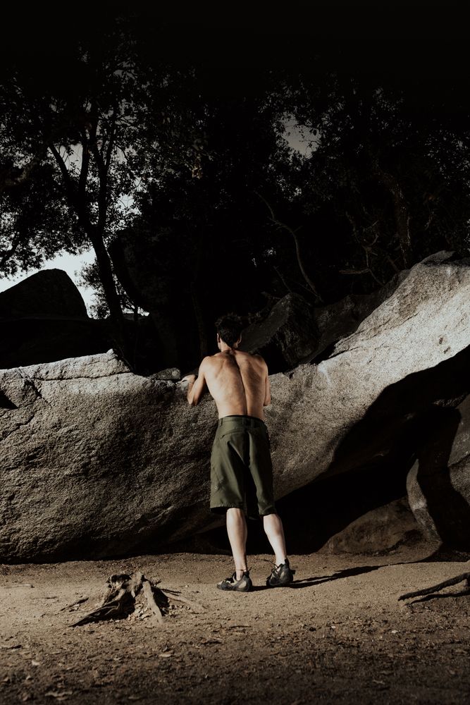 Man practicing rock climbing among large rocks in a forest