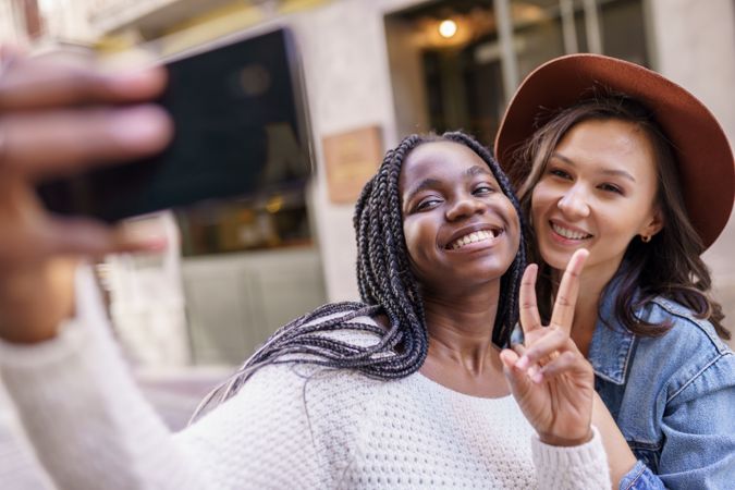 Female friends smiling at smart phone for a selfie