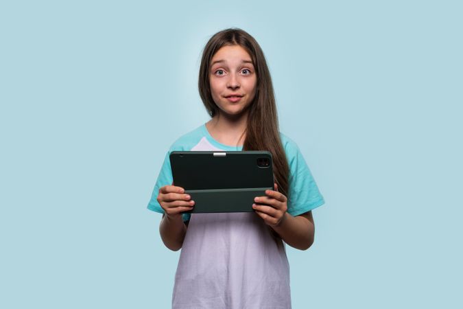 Girl holding tablet, making quirky face
