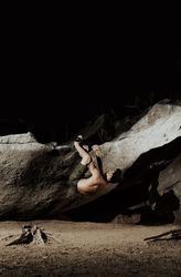 Man practicing rock climbing among large rocks in a forest