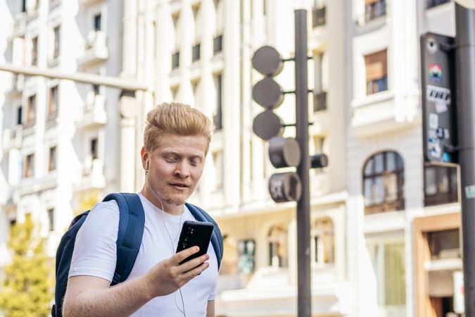 Young Latino man with albinism using smartphone in the city