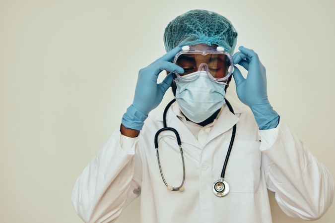 Male doctor putting on protective eyewear for safety