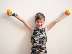 Laughing boy raising hands with oranges up