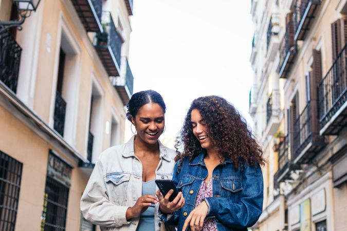 Friends waking in the street using smartphone