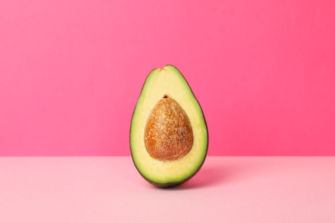 Ripe fresh avocado on pink background, space for text