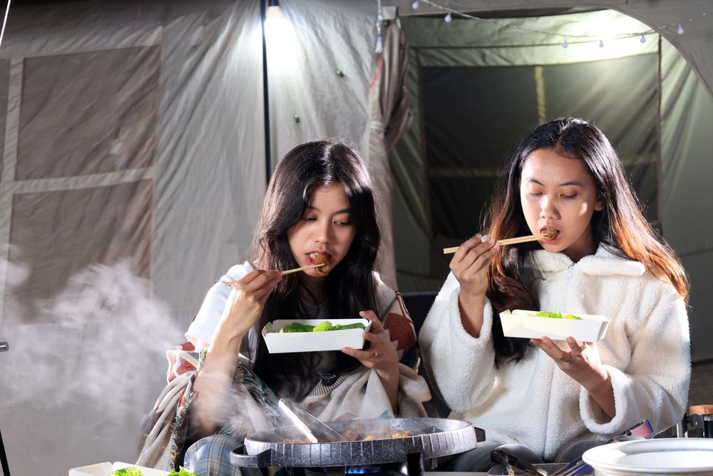 Two Female Asian  Friends Eat  Barbeque  Meat in front of Camping Tent