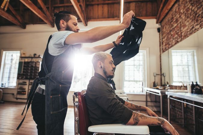 Barber putting salon cape on customer before haircut
