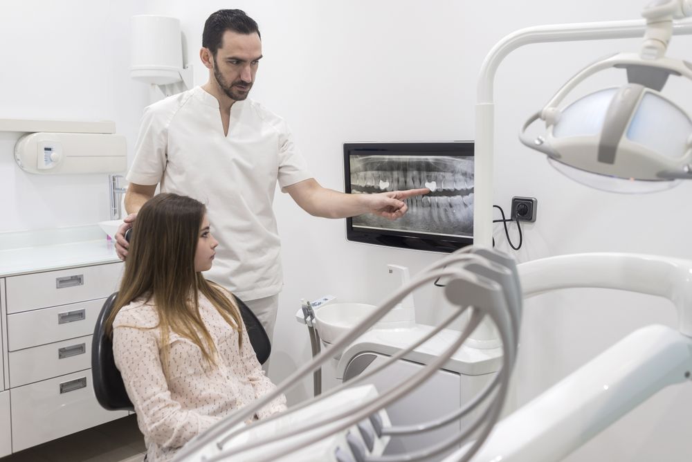 Attractive young dentist showing to his patient radiography of her xray