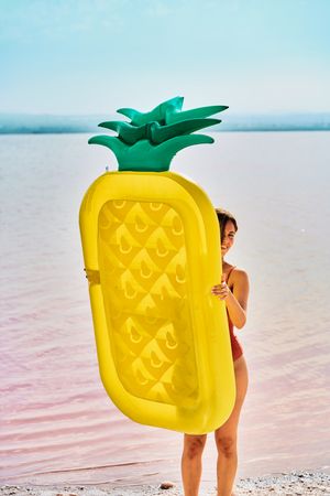 Female with inflatable mattress on coast in summer