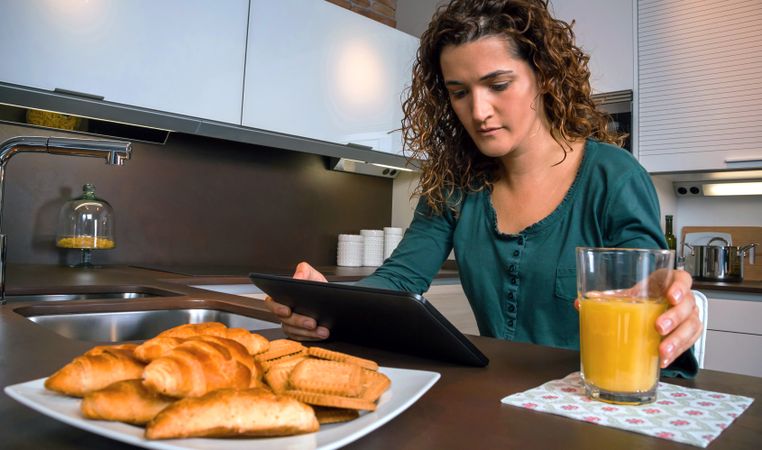 Woman reading tablet during breakfast with orange juice