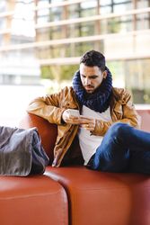 Stylish man using smartphone on couch