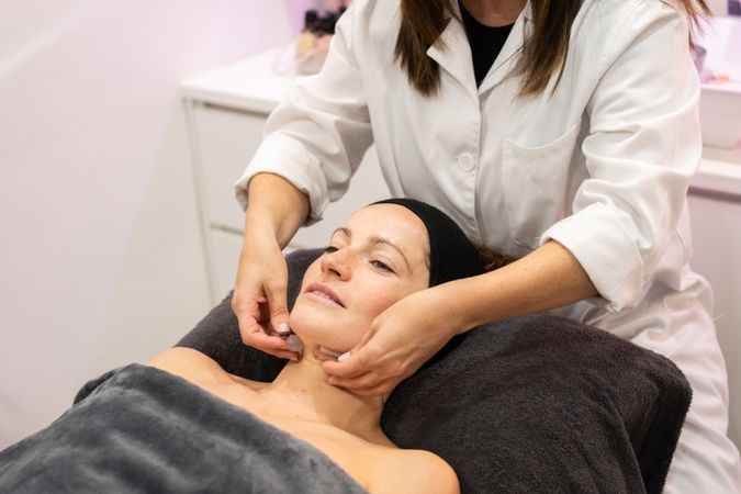 Crop of masseuse doing massage to client in salon