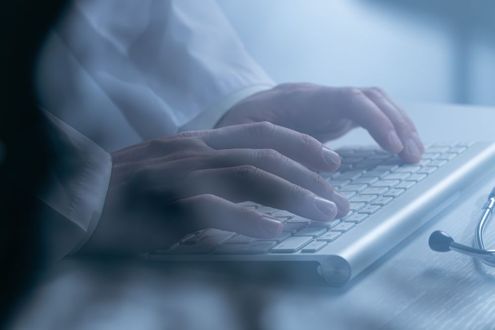 Doctor working at computer keyboard through X-ray film