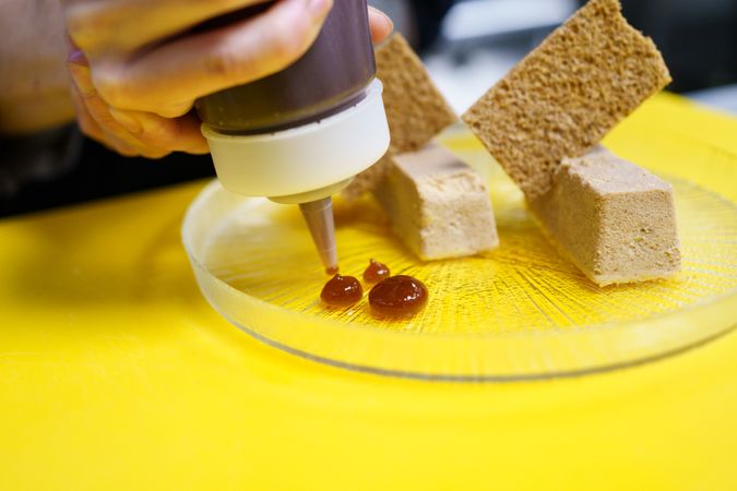 Hand squeezing sauce onto appetizer