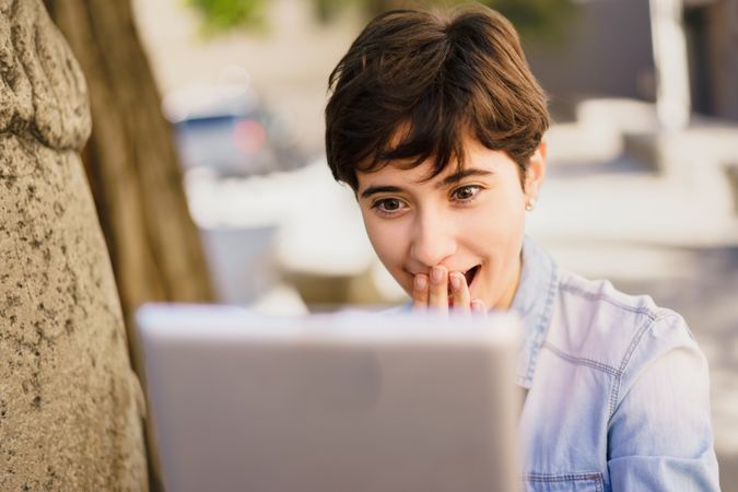 A Joyful Young Woman Enthusiastically Reacting to Her Laptop Screen in an Outdoor Setting