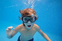 Boy with mouth opened swimming in pool