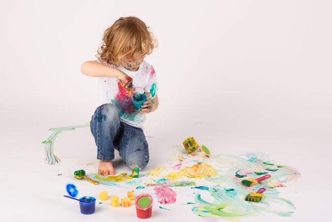 Boy smearing paints on floor