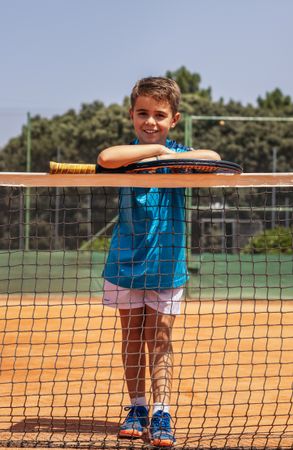 Little boy playing tennis on a dirt court
