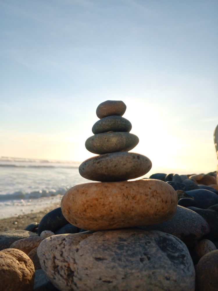 Arrangement of rocks on the beach with calm waves in the background.