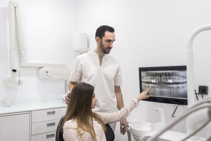Dentist showing to his patient radiography of her mouth in dental clinic