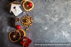 Top view of wooden snowflakes, bird house, dried orange slices and pine cones on marble table 5l1qv4