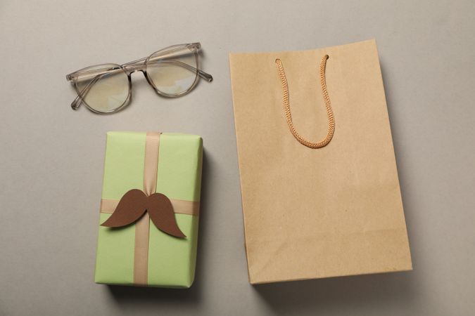 A gift in a craft bag, with a mustache, on a gray background.