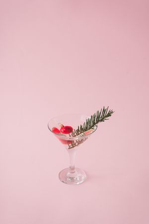 Christmas tree decoration in martini glass on pastel pink background with creative copy space