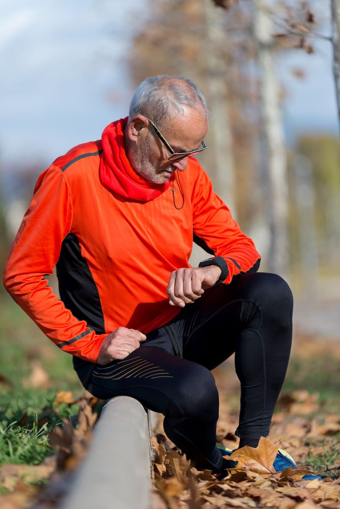 Man in bright windbreaker checking watch in park