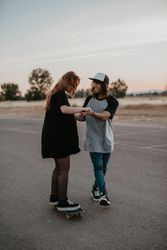 Man helping girlfriend to skate on road