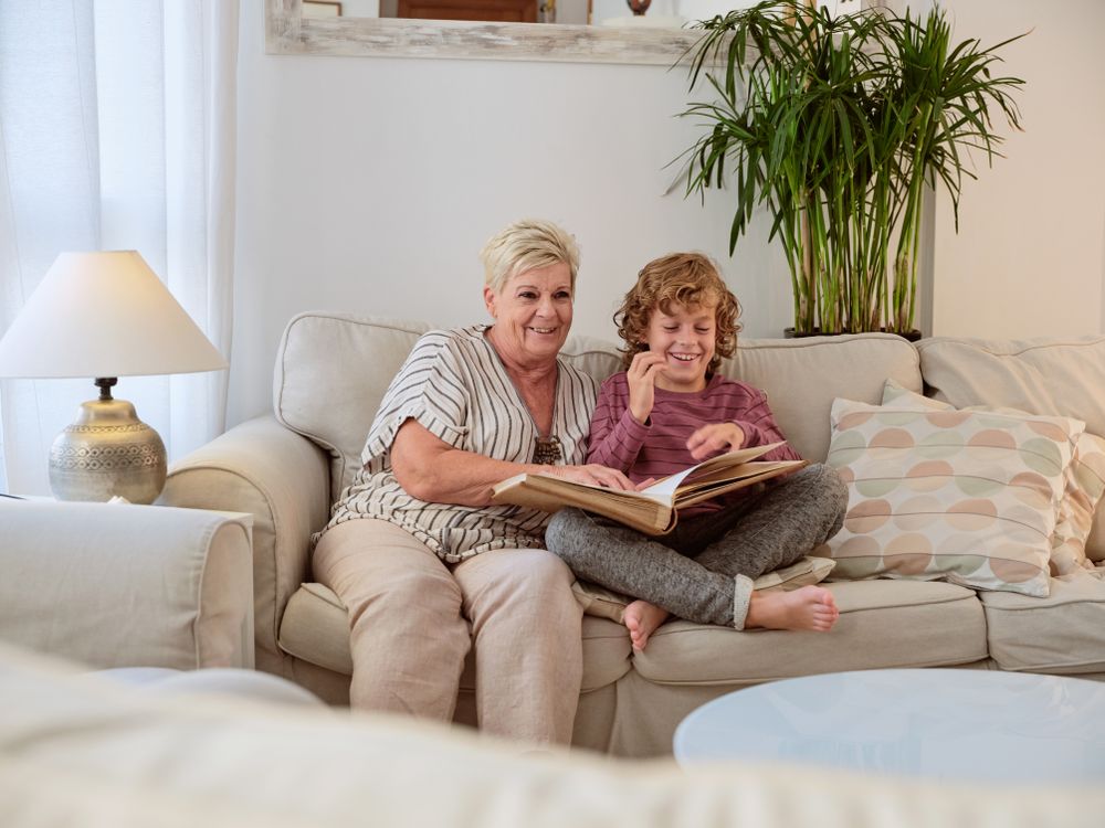 Mature woman with photo album and boy sitting in living room