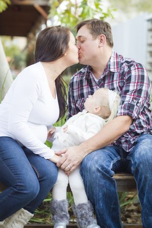 Happy Pregnant Couple Kisses as Baby Girl Watches