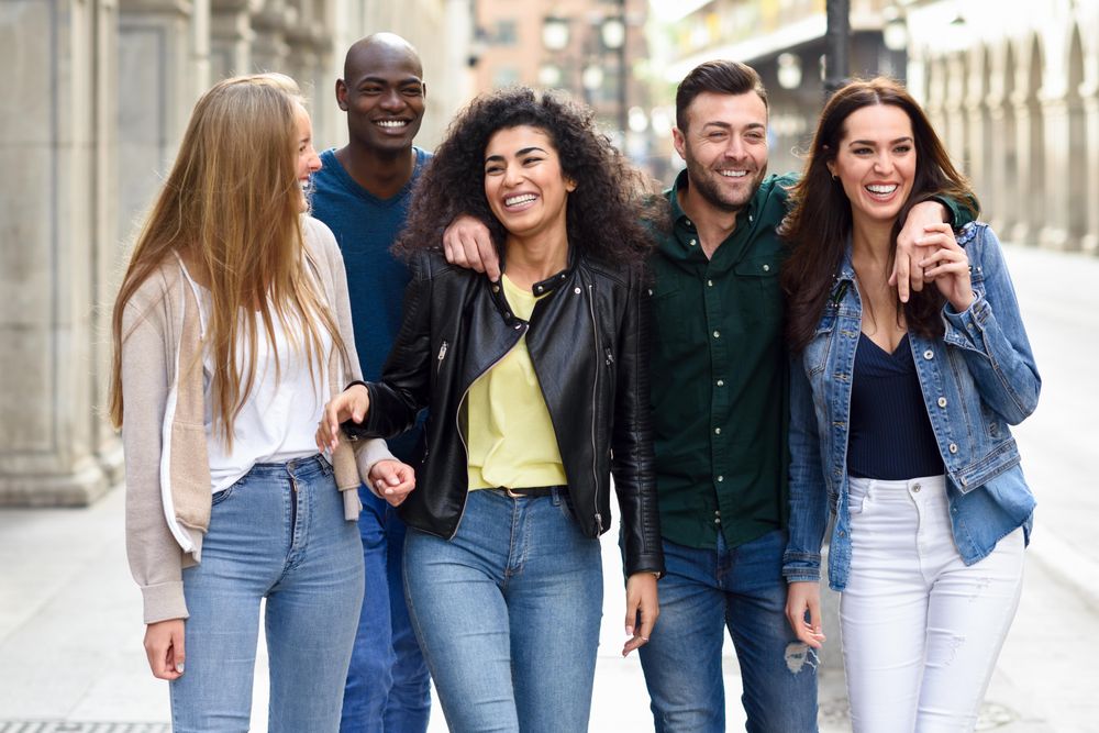 Friends walking down down city street and smiling