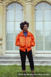 Woman in orange jacket standing on green grass 5rA8d0