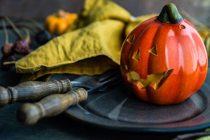 Ceramic jack o'lantern on rustic plate