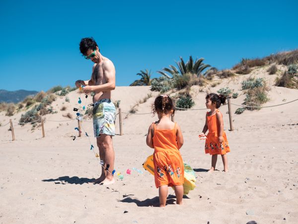 Father and daughters playing with kite on beach