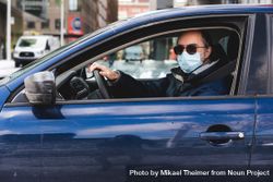 MONTREAL, QUEBEC, CANADA – March 24 2020- A man wearing a mask in his car 0g9MW4
