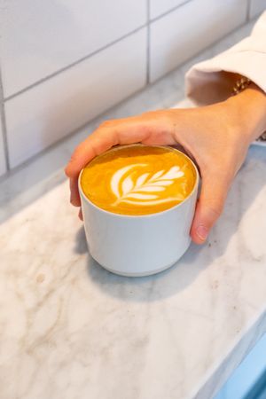 Hand holding cappuccino on marble table