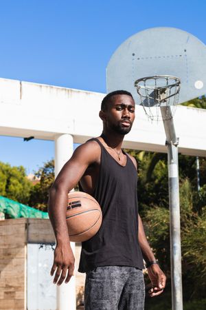 Serious Black man with basketball on sports ground
