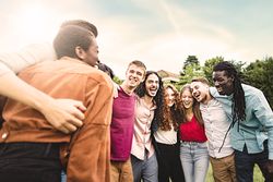 Multiethnic group of joyful young people laughing and interacting together in the park