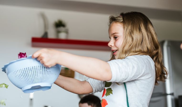 Child washing herbs for salad