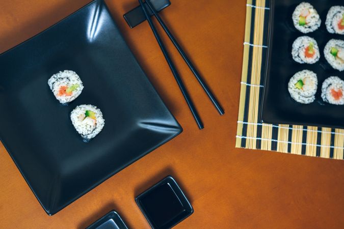 Top view of freshly made sushi rolls on table with chopsticks and mat