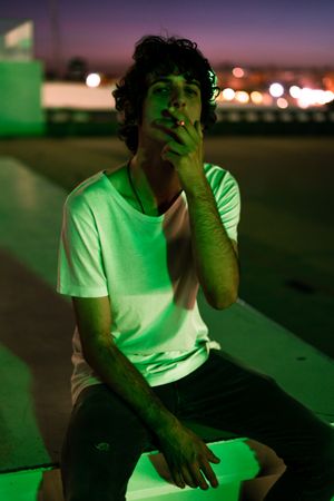 Adult man smoking while looking at camera during sunset