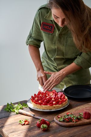 Female cook cutting strawberry cake