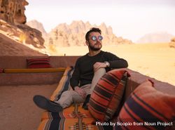 Man sitting on cushion in desert bGG6Vb