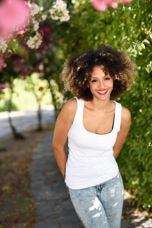Happy Black woman with afro hairstyle smiling in park, vertical