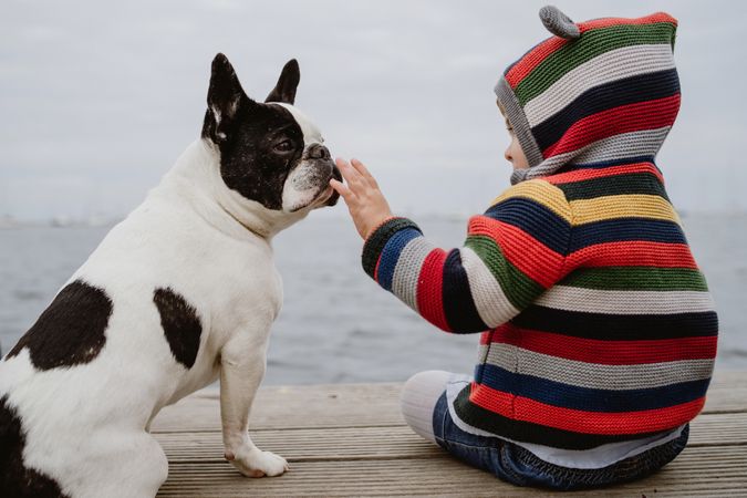 Anonymous kid petting dog on pier