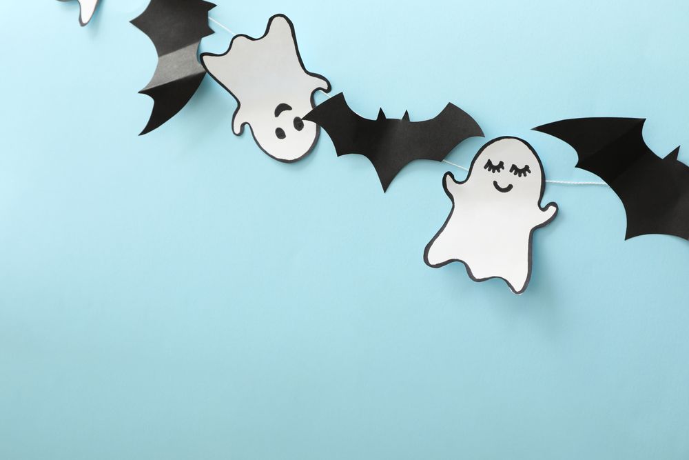 Paper ghosts and bats on blue background, space for text